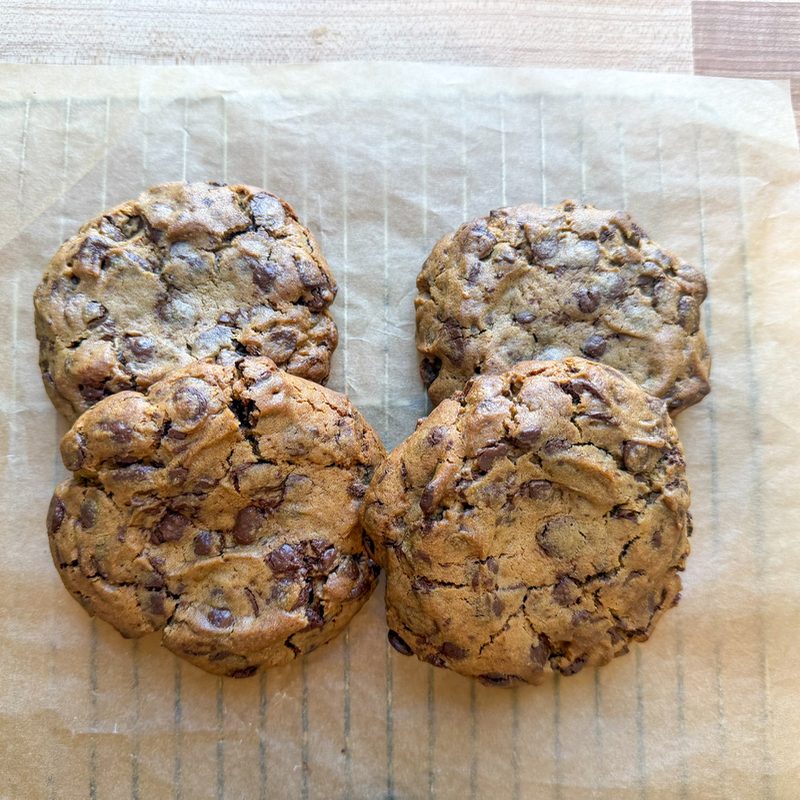 Four organic sourdough chocolate chip cookies on parchment