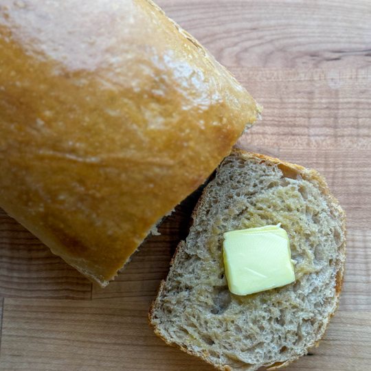 Sourdough sandwich loaf with a buttered slice cut from it